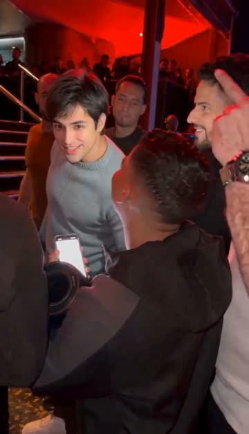The man in the grey sweater turns to the camera in the crowd